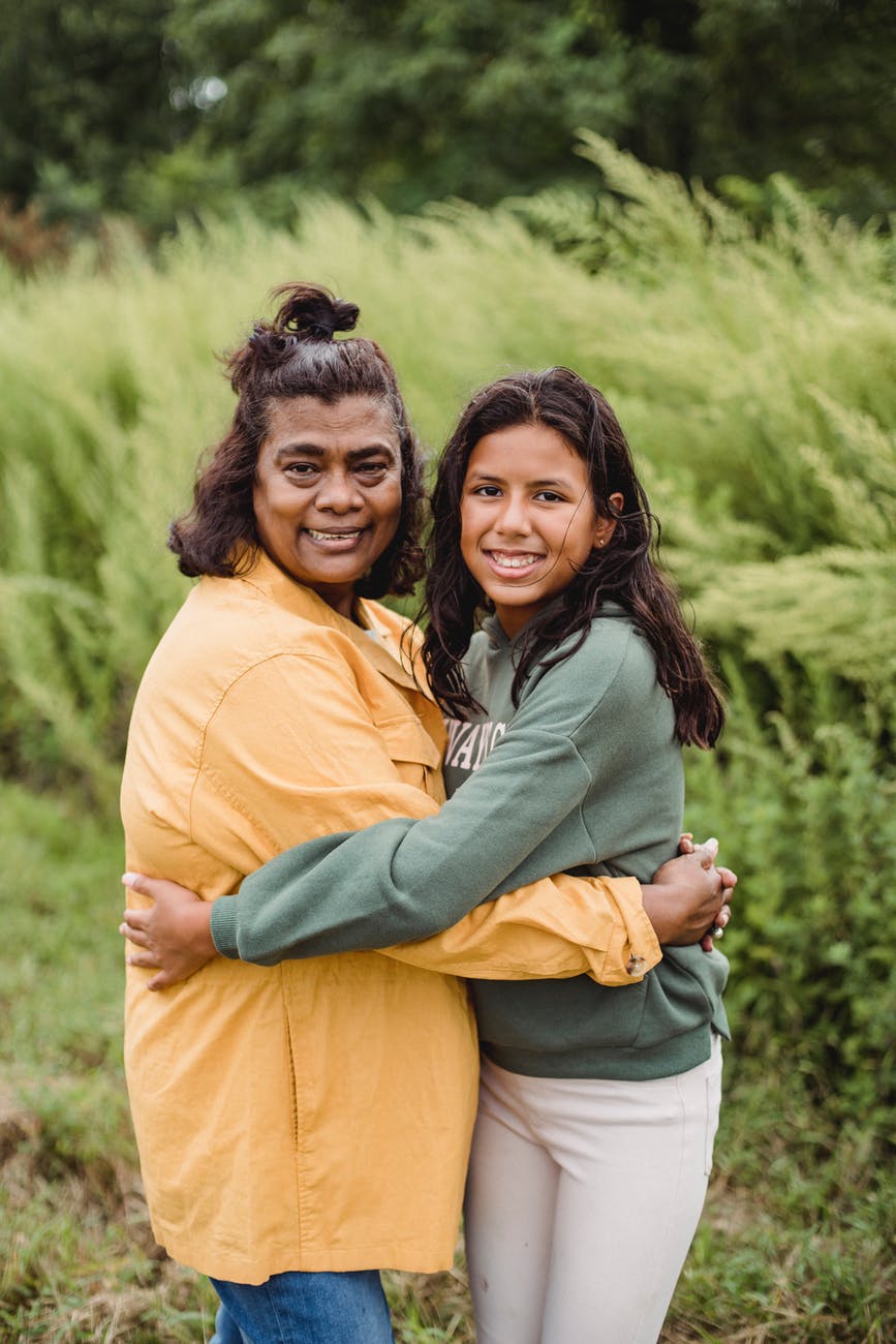cheerful local ethnic women hugging in farm on sunny day
